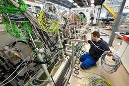 A technician handles the many wires and hoses: at Ampulse's pilot production line being installed in NREL's PDIL.  Credit: Dennis Schroeder